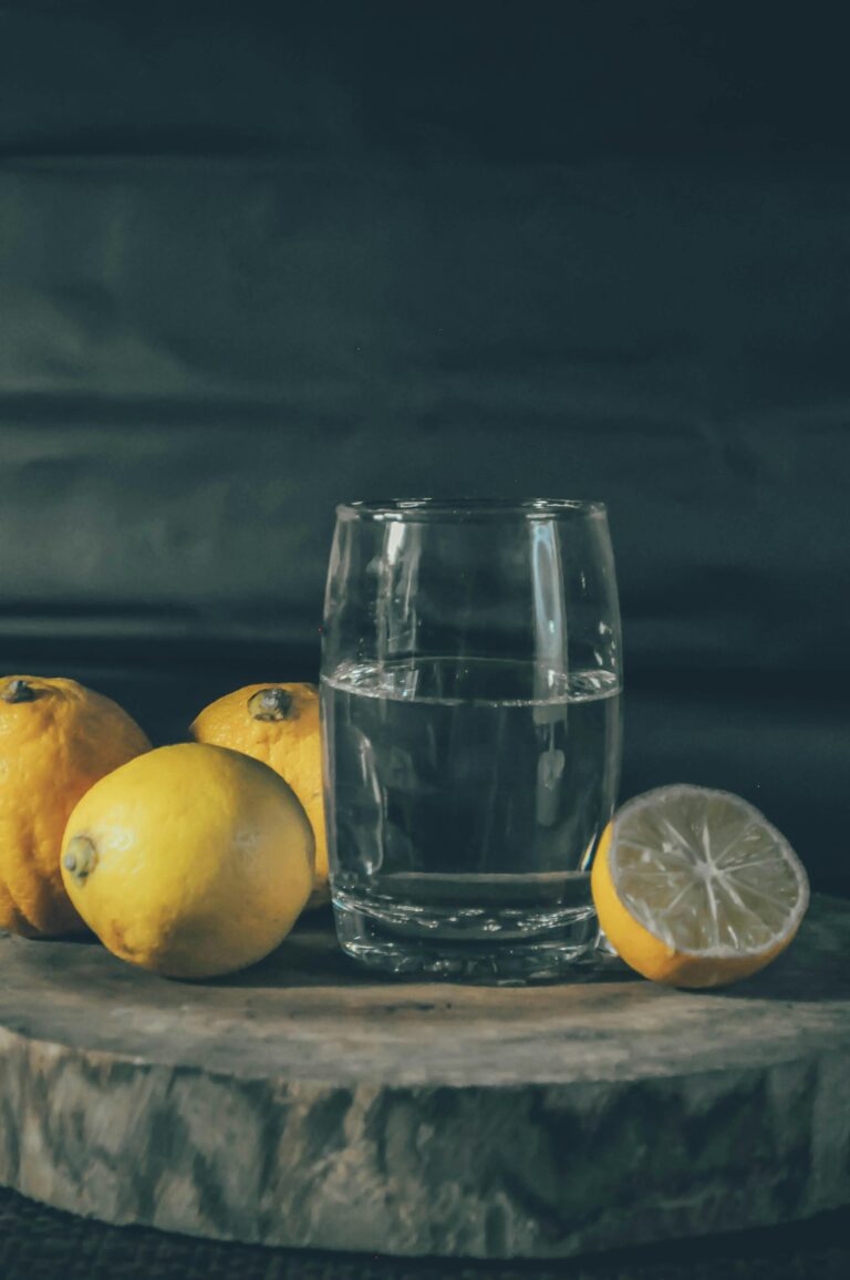 A glass filled halfway with water, surrounded by fresh lemons, symbolizing a positive perspective.