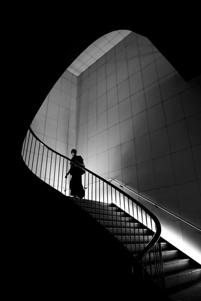 A woman ascending a curved staircase, looking upward, symbolizing healing, resilience, and self-transformation after heartbreak.