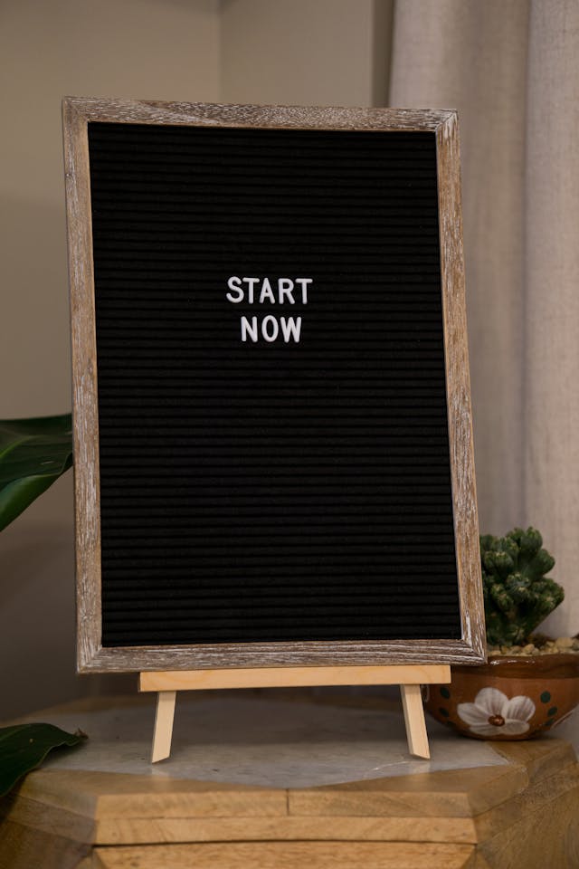 A black chalkboard with "Start Now" written on it, symbolizing the urgency of taking action in career planning before a job transition.