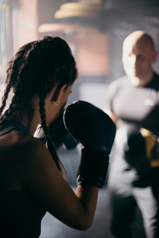 A woman in boxing gloves facing a trainer, symbolizing relationship challenges and the importance of constructive communication.